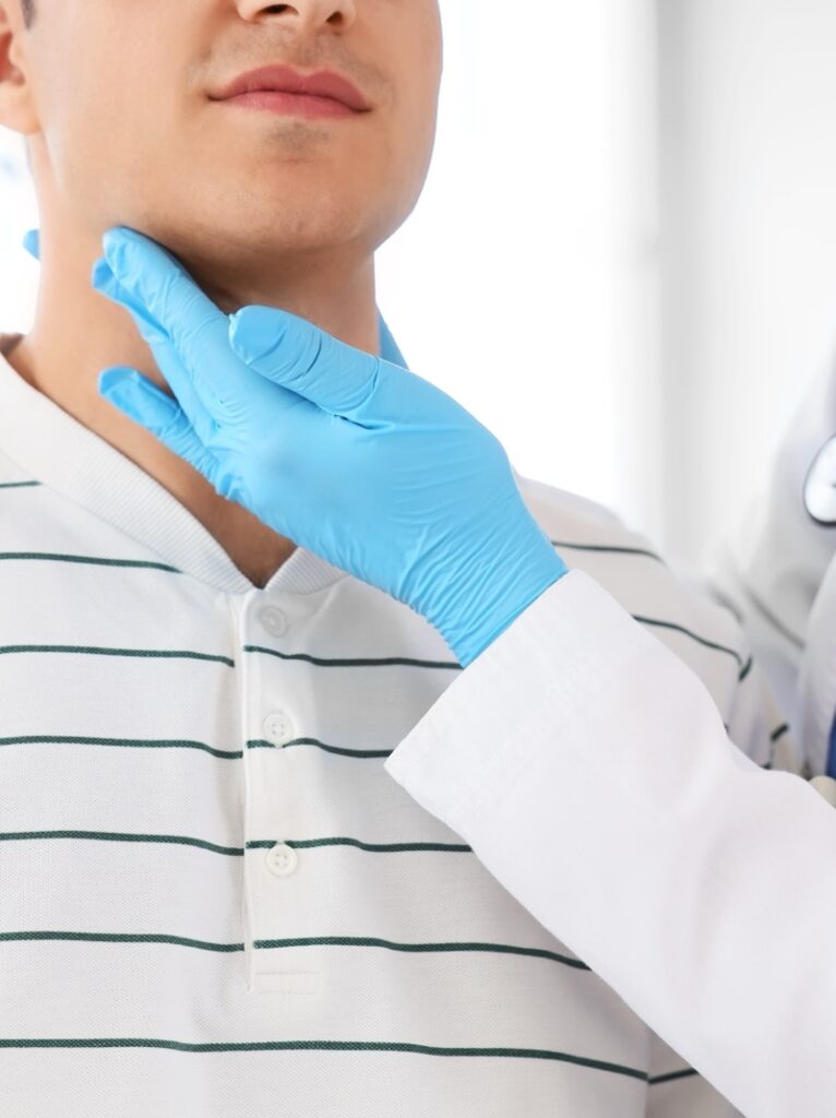 Dermatology provider in gloves checking a patient's neck for a benign lump or cyst